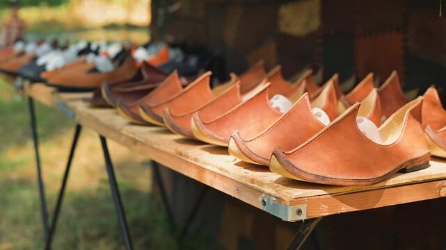 handmade leather shoes at an outdoor market. The shoes are lined up neatly on a table under natural light, attracting potential customers
