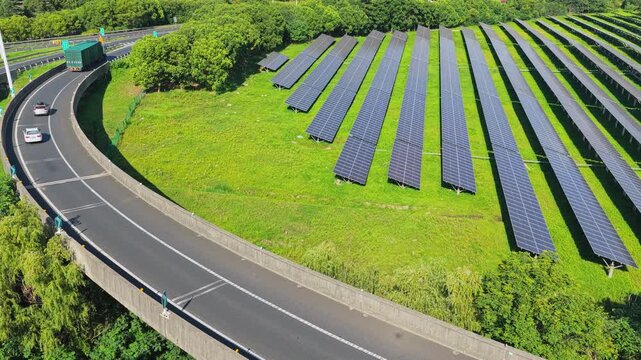 Aerial tracking shot of solar panels beside a busy highway
