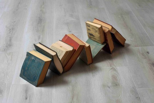 Books arranged in a creative formation on a wooden floor in a simple indoor space