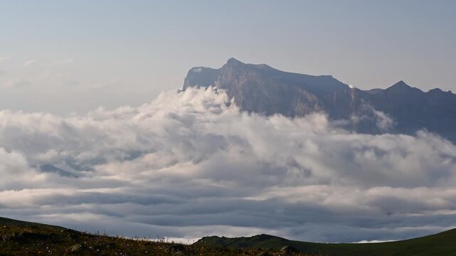 Mountain peak emerges through clouds in a serene landscape timelapse sequence