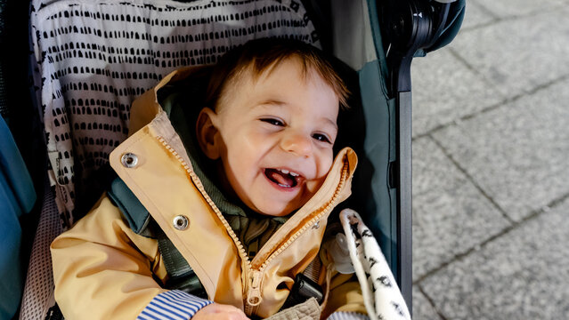 Smiling baby in stroller wearing warm jacket outdoors