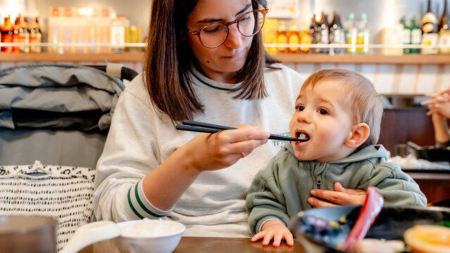 Mother feeding baby steamed white rice with chopsticks