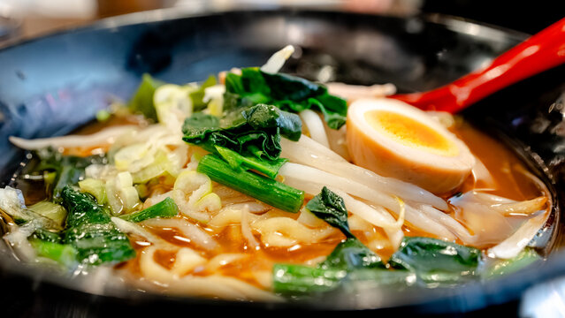 Bowl of ramen with noodle, egg and greens in broth