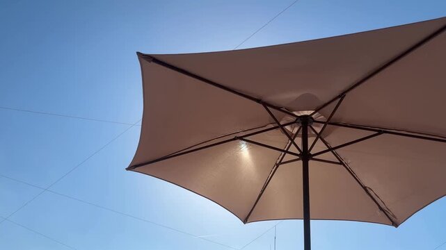 Beige parasol against a bright blue summer sky