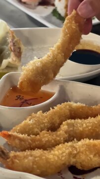 Dipping crispy tempura shrimp into dipping sauce