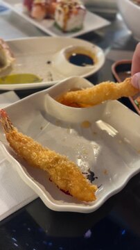 Tempura shrimp dipped in sauce at a Japanese restaurant table