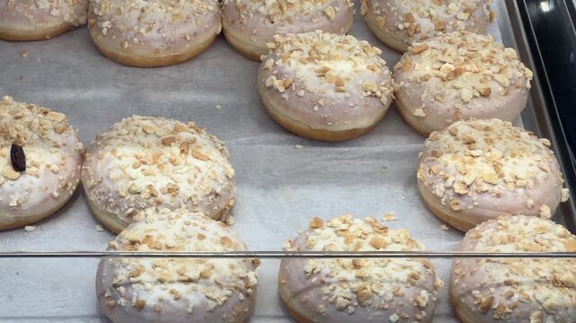 Glazed donuts with nut crumble in a bakery case