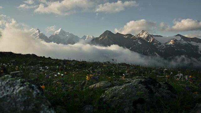 Scenic mountain landscape with flowers and clouds in the foreground and background