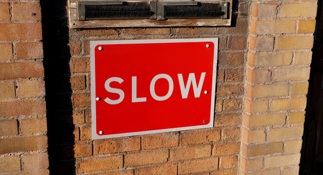 Slow, sign, red, brick wall, speed limit warning sign mounted on exterior brick building facade