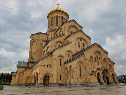 View of the Holy Trinity Cathedral of Tbilisi with its golden dome and stone architecture under a cloudy sky in Tbilisi, Tbilisi, Georgia.