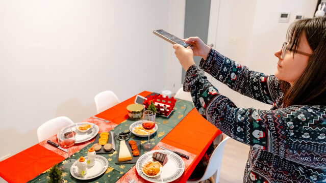 Woman Taking Photo of Christmas Eve Dinner Table with Smartphone