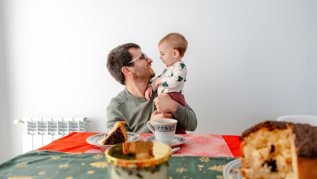Father Holding Baby During New Year Breakfast at Home