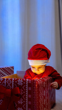 Baby in Santa hat looking into a cozy gift box indoors