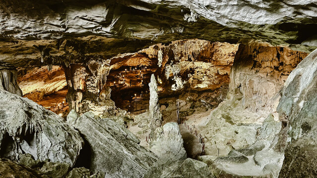 View of the illuminated limestone formations and stalactites inside a large cavern in Vietnam.