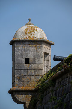 View of a historic stone fort watchtower with a cannon and mossy textures against a clear blue sky in Matosinhos, Porto District, Portugal.
