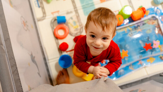 Toddler playing in playpen while adult supervises at home