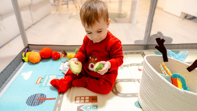 Toddler in red pajamas playing with toy food indoors