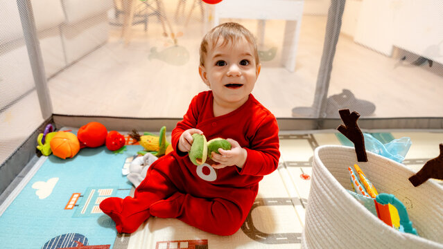Baby playing with toy fruit on play mat at home indoors