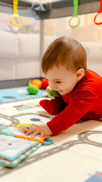 Baby playing with soft toy in playpen on floor mat