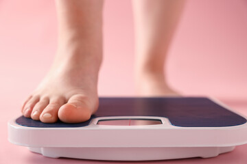 Fototapeta premium Overweight woman on scale against pink background, closeup