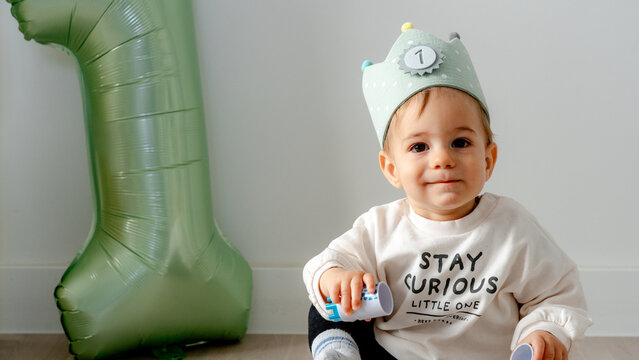 Baby celebrating first birthday with green balloon