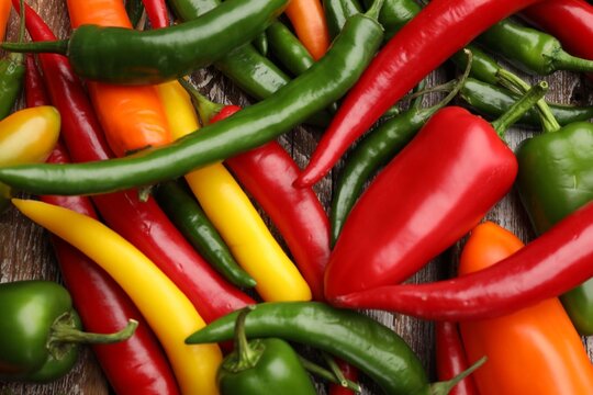 Colorful chili peppers on wooden table, flat lay