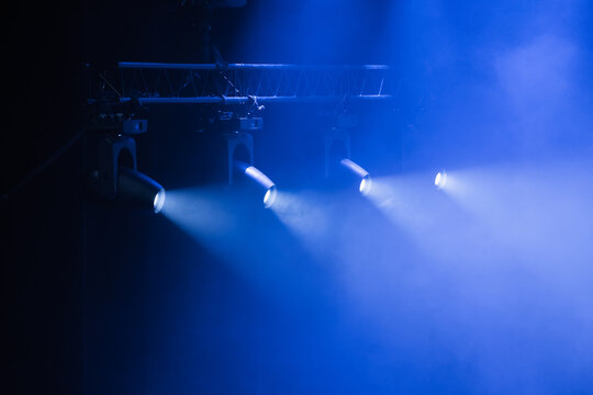 Powerful blue spotlights pierce thick fog on a dark stage, creating a moody theatrical atmosphere ideal for concerts, performances, events, and promotional visuals that highlight lighting design