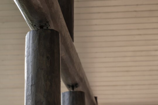 Close-up view of a rustic wooden railing and support posts set against a painted planked ceiling, showcasing natural grain, texture and architectural detail in a cabin or lodge interior