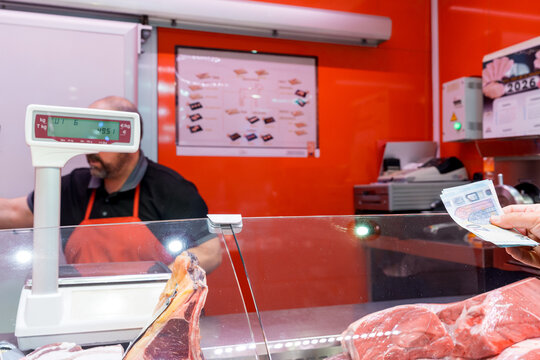 Customer paying cash at butcher counter with fresh meat