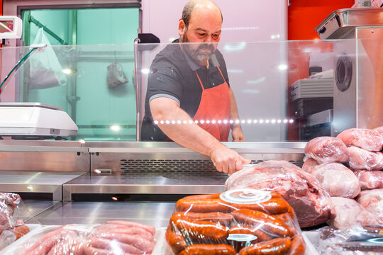 Butcher arranging fresh meat and chorizo sausages at shop counter
