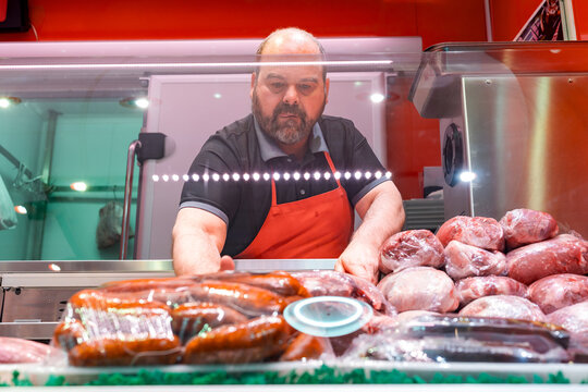 Butcher arranging meat and sausages in market display case