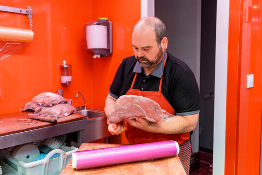 Butcher holding raw meat in red shop kitchen workspace