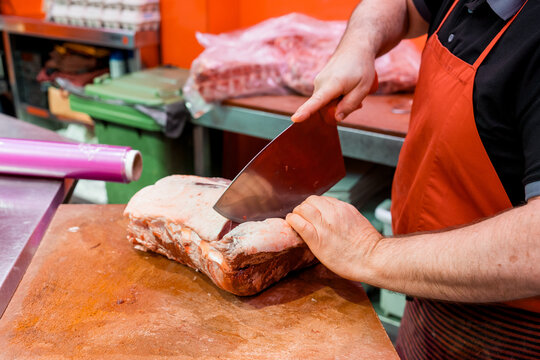 Butcher slicing fresh meat on wooden block in meat shop