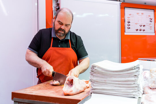 Butcher preparing chicken cut on chopping block in shop