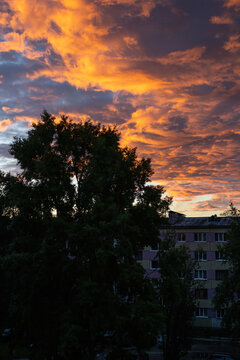 Dramatic orange clouds in the sky over a residential courtyard and apartment building during twilight in the Far North of Russia. Polar night twilight sky concept.