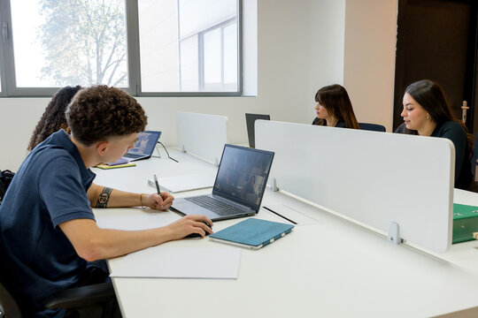 MBA students study with laptops in modern classroom