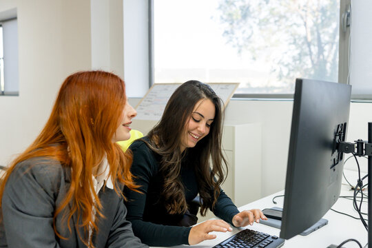 MBA students collaborate at computer in modern classroom
