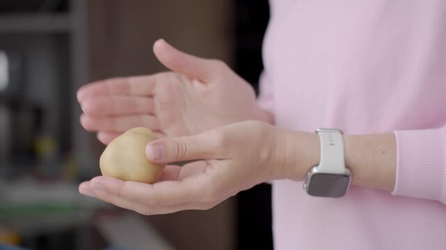 Hands shaping small dough between palms. Concept of homemade baking, pastry preparation and dessert recipe