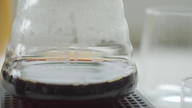 Coffee dripping through filter into glass carafe during pour over brewing. Concept of manual coffee preparation and fresh brewed coffee