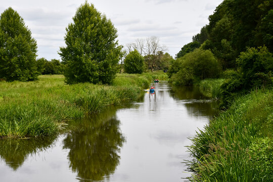 Landscape view of small stream in rural Shropshire on a spring day, with canoes in view as they enjoy the tranquility.