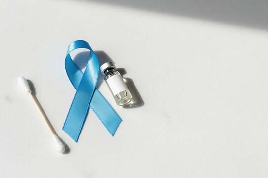 blue awareness ribbon with vaccine vial and cotton swab on white background, concept of health