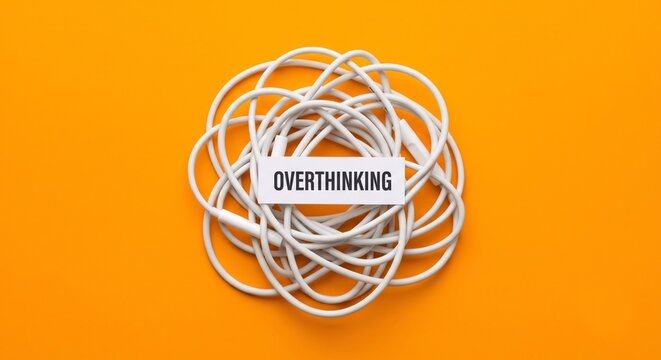 Tangled white cables forming a messy knot with the word overthinking on an orange background