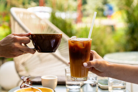 Friends clinking glasses with iced bumble coffee and hot espresso at a cafe