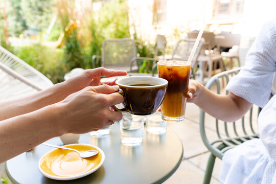 People clinking a hot coffee cup and iced bumble coffee glass at a terrace cafe