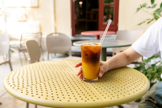 Drinking iced bumble coffee with orange juice on a yellow table at a street cafe