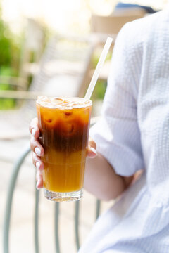 Woman drinking iced bumble coffee with orange juice at a terrace cafe