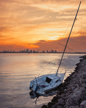 Abandoned Sailboat on Rocky Shore at Sunset in Miami, Florida