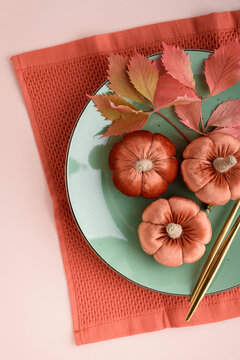 Velvet pumpkins on a plate with autumn leaves and chopsticks for fall celebration