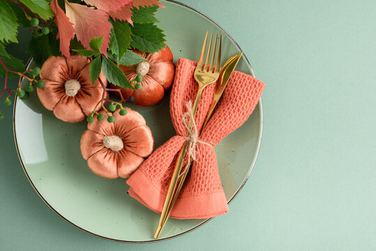 Table setting with fabric pumpkins and gold cutlery for autumn holidays celebration