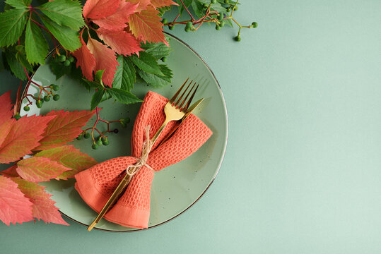 Autumnal Table Setting with Golden Cutlery and Autumn Leaves